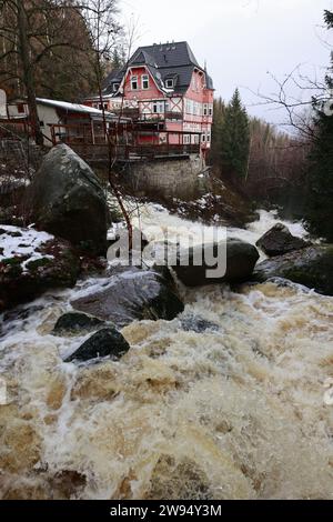 Wernigerode, Germania. 24 dicembre 2023. Masse d'acqua cadono di fronte allo Steinerne Renne inn a Wernigerode. L'acqua piovana fa gonfiare i fiumi, come l'Holtemme qui al 'Steinerne Renne'. La pioggia persistente causa il traboccamento dei torrenti nelle montagne Harz. Il livello di alluvione 2 era già stato superato allo Steinerne Renne durante la notte. Nei prossimi giorni, il disgelo porterà a un ulteriore aumento del livello dell'acqua. Crediti: Matthias Bein/dpa/Alamy Live News Foto Stock