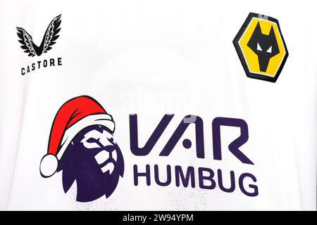 Primo piano del marchio su una maglietta dei Wolverhampton Wanderers con la scritta "VAR Humbug" con un cappello di babbo natale sul logo della Premier League prima della partita di Premier League al Molineux Stadium, Wolverhampton. Data immagine: Domenica 24 dicembre 2023. Foto Stock