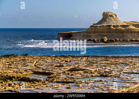 Saline della famiglia Cini a Xwejni Bay, sullo sfondo la White Hill, una bizzarra formazione rocciosa di arenaria calcarea. La famiglia gestisce le saline nel nord di Gozo dal 1860. Negozio di sale Leli tal-Melh a Xwejni, vicino a Marsalforn, Gozo, Malta Foto Stock