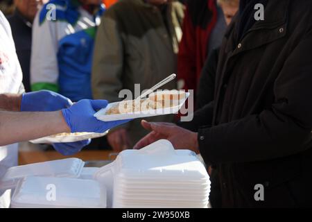 Pola, Croazia. 24 dicembre 2023. Persone che ricevono una porzione di un tradizionale risotto di pesce (risotto ai Fruitti di Mare) durante una tradizionale vigilia di Natale - materiale pubblicitario natalizio presso il mercato cittadino di Pola, Croazia, la vigilia di Natale del 24 dicembre 2023. Foto: SASA Miljevic/PIXSELL credito: Pixsell/Alamy Live News Foto Stock