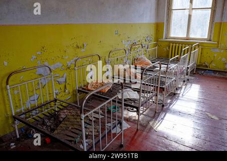 Una camera abbandonata con telai del letto in metallo arrugginito. I letti di vecchi bambini in un asilo abbandonato. L'interno di una stanza in uno degli edifici del Foto Stock