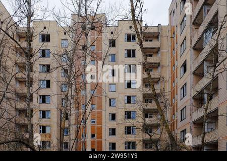 La facciata dell'edificio è grigia e intemprata, con numerose finestre che appaiono scure. Foto Stock