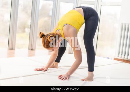 Giovane donna in forma che si allunga in palestra Foto Stock