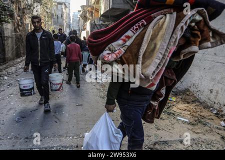 Rafah, territori palestinesi. 24 dicembre 2023. I palestinesi camminano con le loro cose dopo un attacco aereo israeliano sull'edificio della famiglia Abu al-Awf a Rafah, nella Striscia di Gaza meridionale. Dentro sono state uccise due persone. Crediti: Abed Rahim Khatib/dpa/Alamy Live News Foto Stock