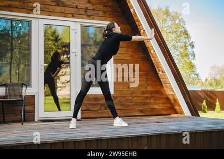 Donna attraente e sportiva che si allena sulla terrazza del bungalow nelle giornate di sole Foto Stock