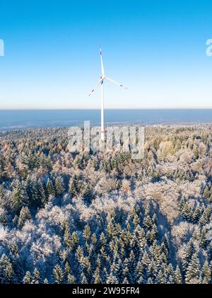 Una turbina eolica solitaria si trova nella foresta invernale innevata sotto un cielo azzurro, vista aerea, Dobel Black Forest, Germania Foto Stock