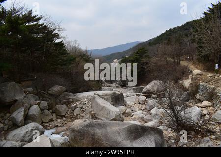 Letto di fiume ghiacciato roccioso che corre lungo un sentiero a piedi nel Parco Nazionale di Bukhansan Foto Stock