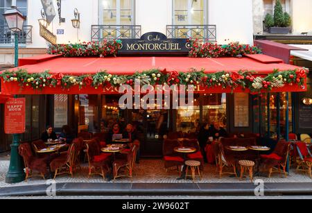 Persone sedute in un tradizionale caffè francese Montorgueil decorato per Natale 2023. Si trova in Rue Montorgueil Street a Parigi, Francia. Foto Stock