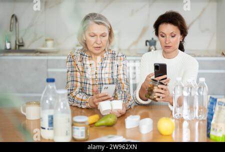 Due donne che scansionano prodotti diversi utilizzando il proprio smartphone Foto Stock