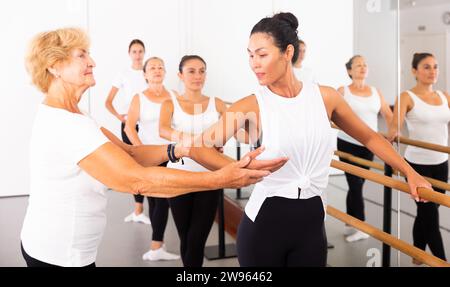 Varie donne anziane che esercitano il balletto si muove con il formatore Foto Stock