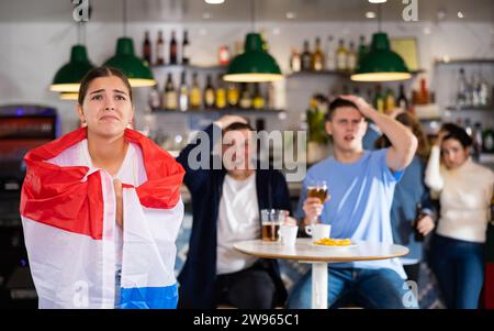 Triste ragazza con amici sconvolta dalla perdita della sua squadra preferita dei Paesi Bassi Foto Stock