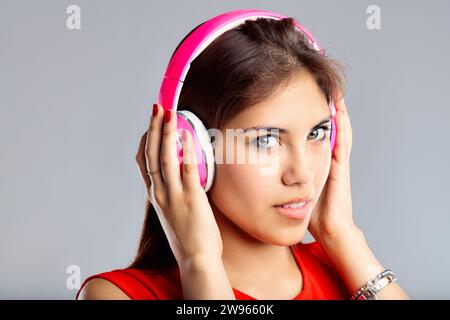 Affascinata dal suono, indossa cuffie rosa, la sua espressione è concentrata e rilassata Foto Stock