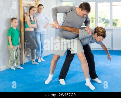 L'uomo in palestra esegue elementi di base del sistema di autodifesa krav maga. Foto Stock