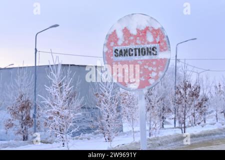 Cartello di avvertimento congelato con parole sanzioni sullo sfondo di un paesaggio invernale Foto Stock