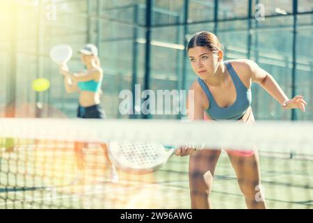 Giovane donna sportiva che gioca a un gioco di padel in campo il giorno di sole Foto Stock