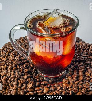 Tazza di caffè freddo su una pila di boffee appena tostato Foto Stock