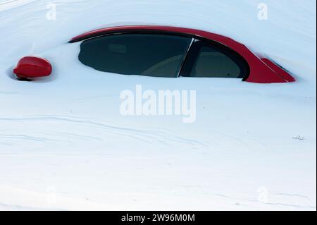 Auto rossa sepolta nella neve dopo la bufera di neve Foto Stock