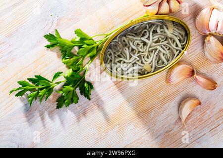 Immagine di anguille sottaceto in lattina aperta con aglio a tavola, nessuno Foto Stock