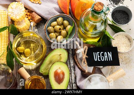 Avocado, mandorle, semi, semi di lino, olive e oli su sfondo chiaro, vista dall'alto. Concetto di oli alternativi. Foto Stock