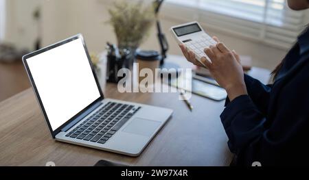Modello dello schermo di un notebook, schermo vuoto vuoto sulla scrivania mentre lavora una donna d'affari Foto Stock