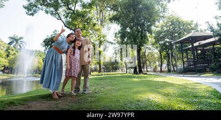 I nonni si divertono con la nipote nel parco circondato dal verde e dalla serenità. trascorrere momenti felici e allegri insieme in un ambiente verde lussureggiante Foto Stock