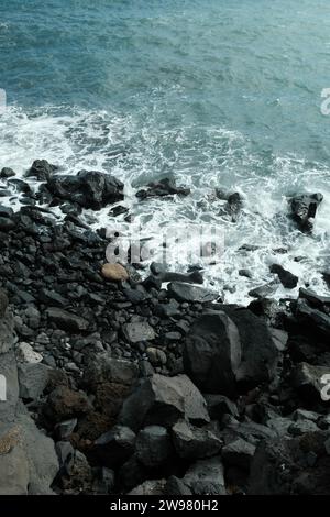 Un paesaggio roccioso su una costa, con onde che si infrangono sullo sfondo Foto Stock