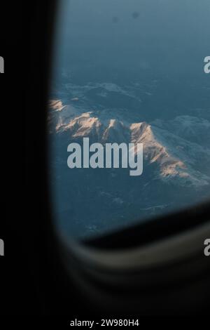 Una vista aerea delle montagne catturate attraverso una finestra dell'aereo, vista dall'interno dell'aereo Foto Stock