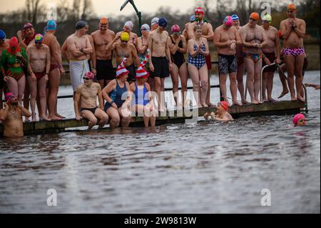 I nuotatori si riuniscono presto per la tradizionale gara di nuoto mattutina di Natale del Regno Unito nel lago Serpentine di Londra, Hyde Park. Chiamati i nuotatori della Peter Pan Cup hanno gareggiato nei cappelli di Babbo Natale dal 1864. Alle 9:00, i membri del Serpentine Swimming Club si tuffano nell'acqua ghiacciata di 7 gradi centigradi per correre per 100 metri (91 metri). L'autore J M Barrie, che viveva nelle vicinanze, Peter Pan, è stato associato alla gara di Natale del 1903. Foto Stock