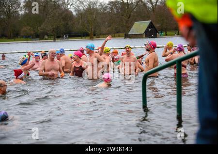 I nuotatori si riuniscono presto per la tradizionale gara di nuoto mattutina di Natale del Regno Unito nel lago Serpentine di Londra, Hyde Park. Chiamati i nuotatori della Peter Pan Cup hanno gareggiato nei cappelli di Babbo Natale dal 1864. Alle 9:00, i membri del Serpentine Swimming Club si tuffano nell'acqua ghiacciata di 7 gradi centigradi per correre per 100 metri (91 metri). L'autore J M Barrie, che viveva nelle vicinanze, Peter Pan, è stato associato alla gara di Natale del 1903. Foto Stock