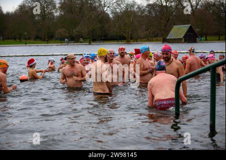 I nuotatori si riuniscono presto per la tradizionale gara di nuoto mattutina di Natale del Regno Unito nel lago Serpentine di Londra, Hyde Park. Chiamati i nuotatori della Peter Pan Cup hanno gareggiato nei cappelli di Babbo Natale dal 1864. Alle 9:00, i membri del Serpentine Swimming Club si tuffano nell'acqua ghiacciata di 7 gradi centigradi per correre per 100 metri (91 metri). L'autore J M Barrie, che viveva nelle vicinanze, Peter Pan, è stato associato alla gara di Natale del 1903. Foto Stock