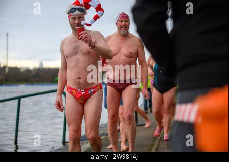 I nuotatori si riuniscono presto per la tradizionale gara di nuoto mattutina di Natale del Regno Unito nel lago Serpentine di Londra, Hyde Park. Chiamati i nuotatori della Peter Pan Cup hanno gareggiato nei cappelli di Babbo Natale dal 1864. Alle 9:00, i membri del Serpentine Swimming Club si tuffano nell'acqua ghiacciata di 7 gradi centigradi per correre per 100 metri (91 metri). L'autore J M Barrie, che viveva nelle vicinanze, Peter Pan, è stato associato alla gara di Natale del 1903. Foto Stock