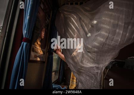 Un giovane cinese che guarda fuori dal finestrino di un treno. Foto Stock