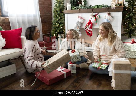 Amici che ridono e scambiano regali di natale Foto Stock