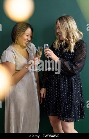 Due donne vestite di fantasia brindando con flauti di champagne Foto Stock