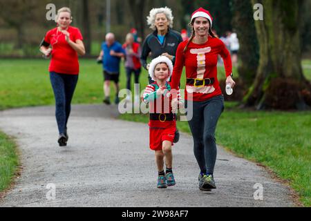 Chippenham, Wiltshire, Regno Unito. 25 dicembre 2023. I corridori sono fotografati mentre prendono parte a una corsa di 5 km nel parco di Monkton Park, Chippenham, il giorno di Natale di prima mattina. La partenza anticipata non ha fatto nulla per attenuare lo spirito natalizio delle 200-300 persone che hanno partecipato all'evento, molte delle quali si sono vestite con abiti eleganti. Credito: Lynchpics/Alamy Live News Foto Stock