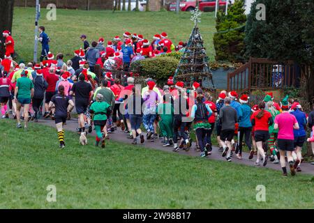 Chippenham, Wiltshire, Regno Unito. 25 dicembre 2023. I corridori sono fotografati mentre prendono parte a una corsa di 5 km nel parco di Monkton Park, Chippenham, il giorno di Natale di prima mattina. La partenza anticipata non ha fatto nulla per attenuare lo spirito natalizio delle 200-300 persone che hanno partecipato all'evento, molte delle quali si sono vestite con abiti eleganti. Credito: Lynchpics/Alamy Live News Foto Stock