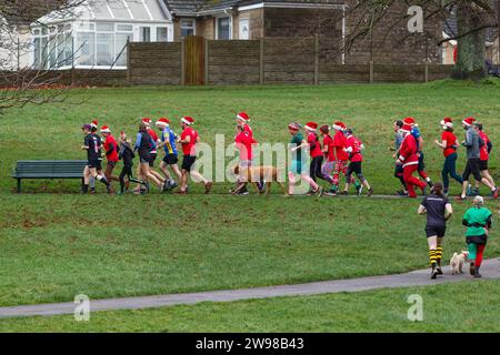 Chippenham, Wiltshire, Regno Unito. 25 dicembre 2023. I corridori sono fotografati mentre prendono parte a una corsa di 5 km nel parco di Monkton Park, Chippenham, il giorno di Natale di prima mattina. La partenza anticipata non ha fatto nulla per attenuare lo spirito natalizio delle 200-300 persone che hanno partecipato all'evento, molte delle quali si sono vestite con abiti eleganti. Credito: Lynchpics/Alamy Live News Foto Stock