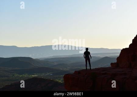 Persona in piedi su una sporgenza di pietra che si affaccia sul paesaggio desertico dell'Arizona dalla Cathedral Rock di Sedona Foto Stock