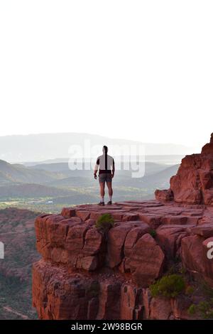 Persona in piedi su una sporgenza di pietra che si affaccia sul paesaggio desertico dell'Arizona dalla Cathedral Rock di Sedona Foto Stock