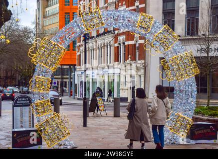 Londra, Regno Unito. 25 dicembre 2023. La gente passeggia accanto alle decorazioni natalizie nel West End di Londra in un giorno di Natale intramontabile. Le temperature miti, che raggiungono i 13 gradi Celsius nella capitale, seguono la vigilia di Natale più calda degli ultimi 20 anni. Credito: Vuk Valcic/Alamy Live News Foto Stock