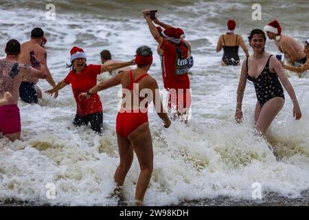 In mezzo all'allegria festiva e alle vivaci celebrazioni sulla spiaggia di Brighton, dove centinaia di persone si sono riunite per l'annuale giorno di Natale nuotano nel grezzo cahnnel inglese dove la temperatura era di 10,4 m. Foto Stock