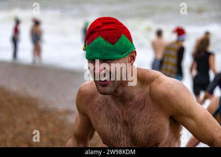 In mezzo all'allegria festiva e alle vivaci celebrazioni sulla spiaggia di Brighton, dove centinaia di persone si sono riunite per l'annuale giorno di Natale nuotano nel grezzo cahnnel inglese dove la temperatura era di 10,4 m. Foto Stock