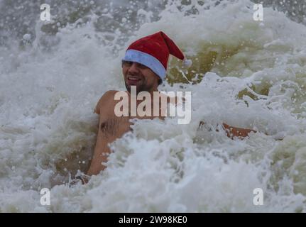 In mezzo all'allegria festiva e alle vivaci celebrazioni sulla spiaggia di Brighton, dove centinaia di persone si sono riunite per l'annuale giorno di Natale nuotano nel grezzo cahnnel inglese dove la temperatura era di 10,4 m. Foto Stock