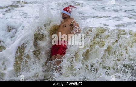 In mezzo all'allegria festiva e alle vivaci celebrazioni sulla spiaggia di Brighton, dove centinaia di persone si sono riunite per l'annuale giorno di Natale nuotano nel grezzo cahnnel inglese dove la temperatura era di 10,4 m. Foto Stock