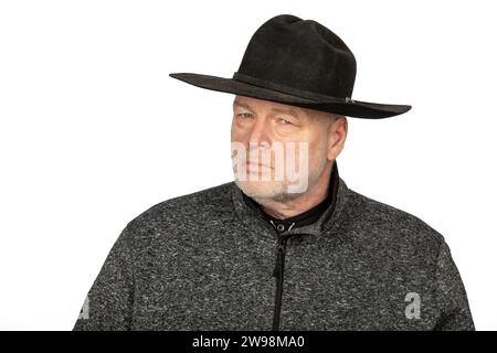 Uomo caucasico di mezza età con cappello da cowboy nero che fissa intensamente - foto isolata su sfondo bianco Foto Stock