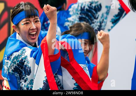 Primo piano, giovane ballerino giapponese yosakoi che danza con il braccio sollevato con un pugno stretto mentre applaude. Indossa la tunica yukata blu e bianca. Foto Stock