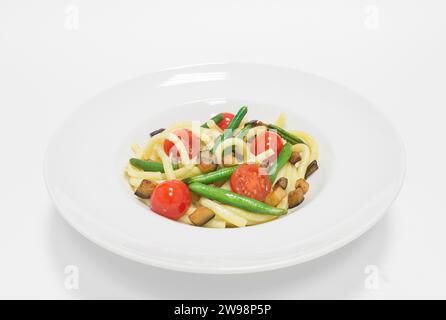 Pasta gourmet con pomodori ciliegini, fagioli verdi e zucchine. Vista dall'alto. Sfondo bianco. Concetto di alimentazione sana. Supporti misti Foto Stock