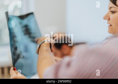 Visita dell'ufficio medico: Il medico esperto esamina i polmoni dei pazienti anziani, esamina la pellicola a raggi X, fornisce cure professionali e diagnosi. Foto Stock