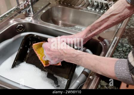 Vassoio del forno da cucina per lavare le donne anziane nel lavandino Foto Stock