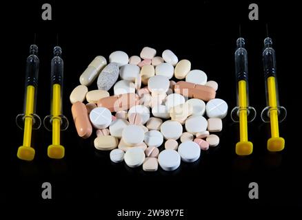 Primo piano di pillole e siringhe diverse su sfondo nero. Foto Stock
